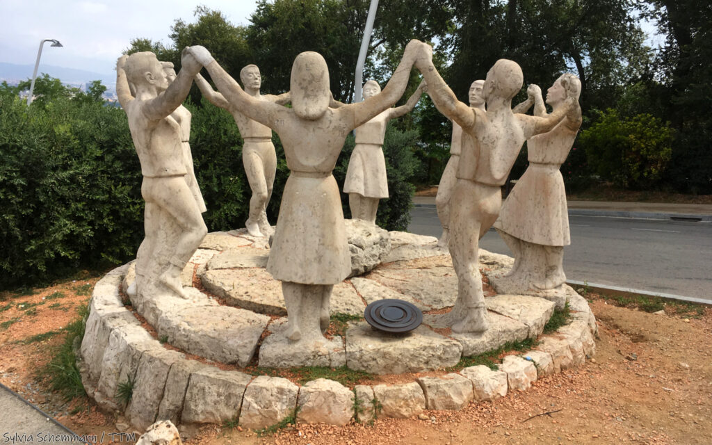 Ein Denkmal für den Sardana-Tanz: Tanzende Menschen, die im Kreis stehen und sich an den Händen halten