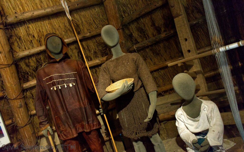 Schaufensterpuppen mit steinzeitlicher Kleidung im Archäologischen Freilichtmuseum Oerlinghausen