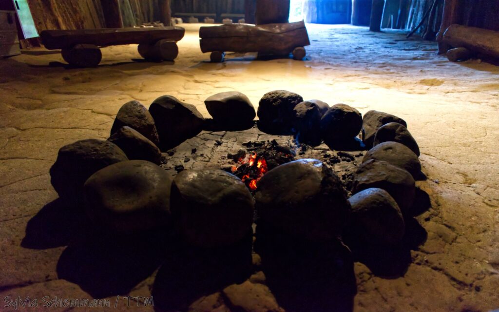 Glut in einer runden Feuerstelle, die mit großen Steinen eingefasst ist im Archäologischen Freilichtmuseum Oerlinghausen