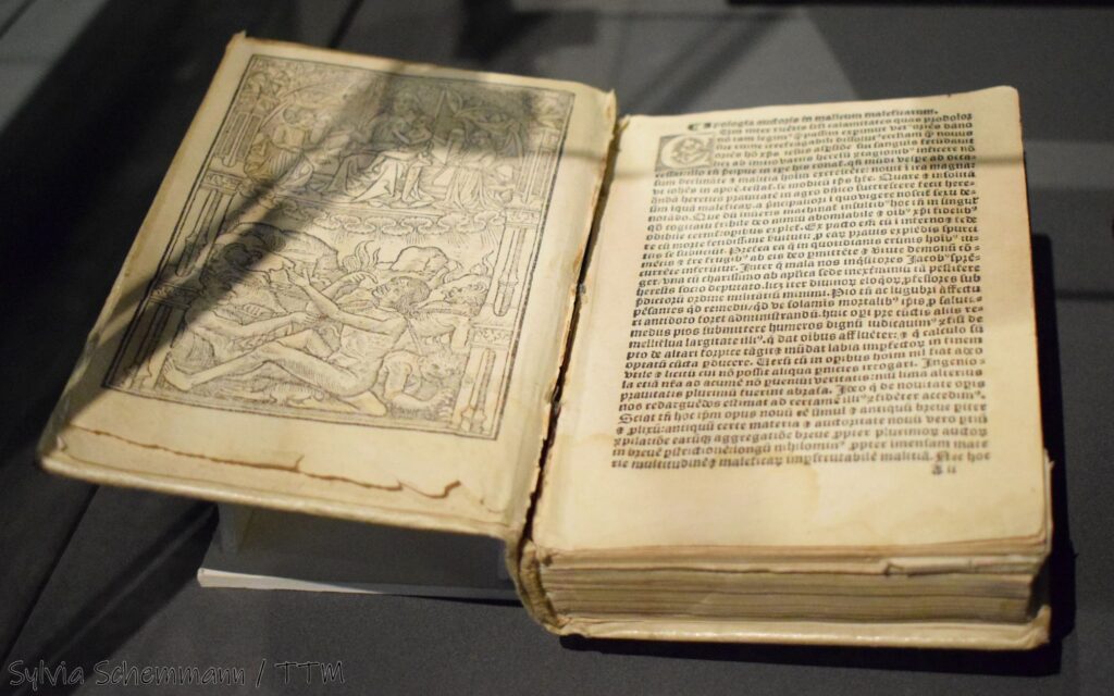 Ein aufgeschlagenes historisches Buch, mit einer Zeichnung auf der linken seit und Schrift auf der rechten.
