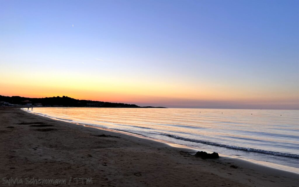 Der Strand von Vieste mit dem Meer bei Sonnenuntergang, der Himmel hat sich am Horizont orange verfärbt