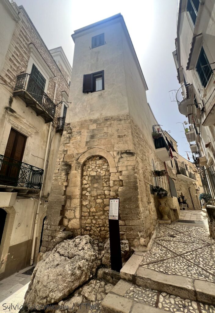 Blick auf eine Altstadtgasse in Vieste, in der Mitte ist der überbaute Felsen Chianca Amara zu sehen.