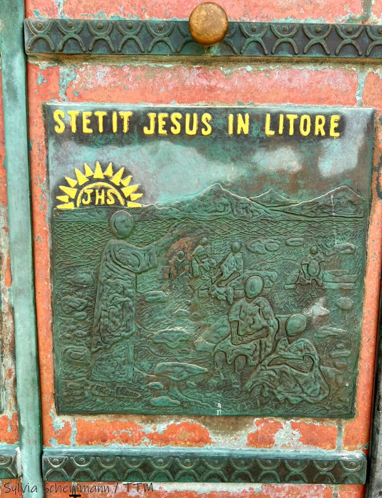 Detail der Kirchentür, erkennbar ist ein Relief und der goldene Schriftzug "Stetit Jesus in litore"