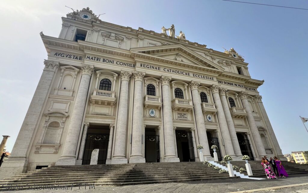 Eine weiße Kirche mit Säulenverzierung an der Fassade.