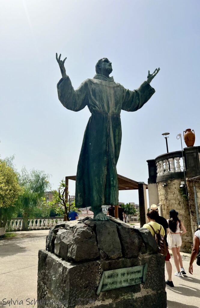 Die Statue eines Mannes in Kutte, der gen Himmel schaut und beide Hände in Richtung Himmel gehoben hat.